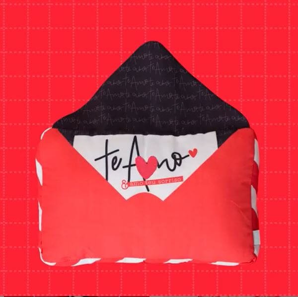Almofada vermelha em formato de envelope com estampa que simboliza uma carta, com a frase "te amo".