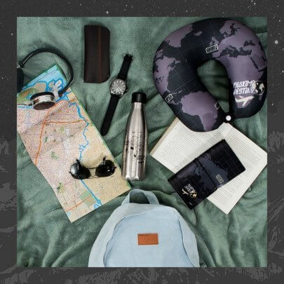 fundo verde com almofada de pescoço, mochila, mapa, óculos de sol, garrafa térmica e caderno de anotações