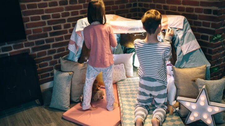duas crianças de pijama com lençóis esperando comidas para festa do pijama