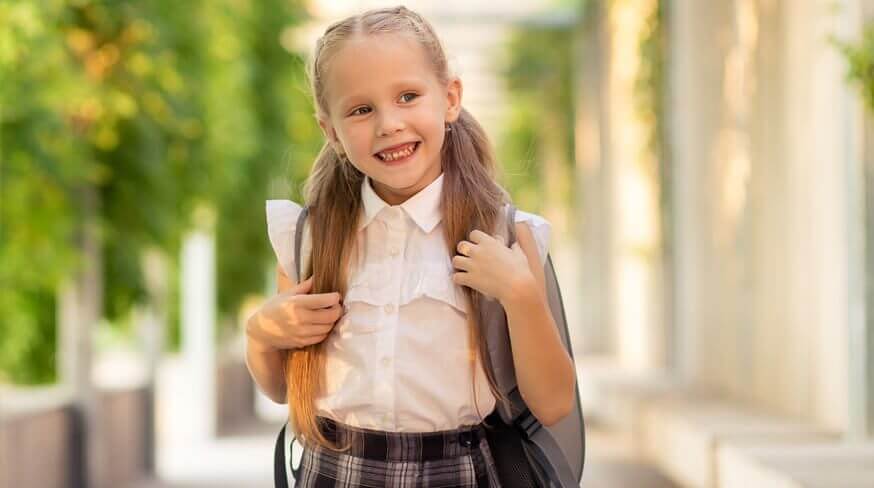 menina loira com mochila nas costas preparada para a volta as aulas