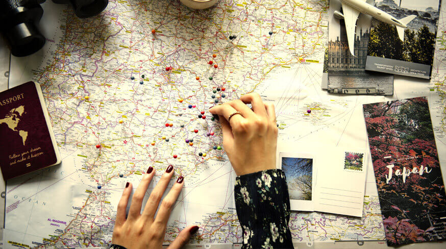 pessoa planejando viagem com um mapa, alfinetes espalhados e roteiros