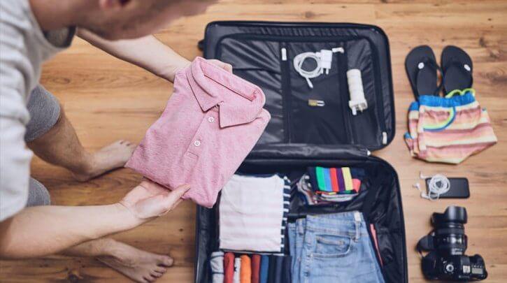 pessoa arrumando mala com acessórios para viagem