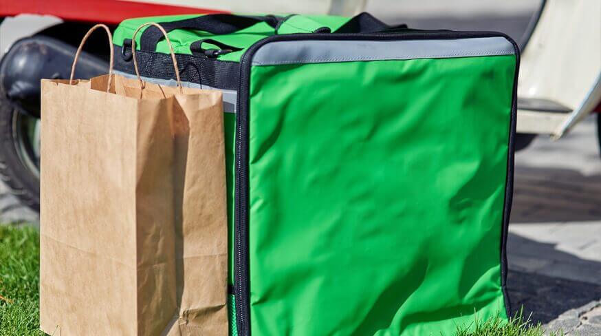 bolsa térmica verde ao lado de uma sacola de papelão