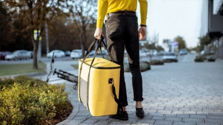 homem carregando bolsa térmica amarela