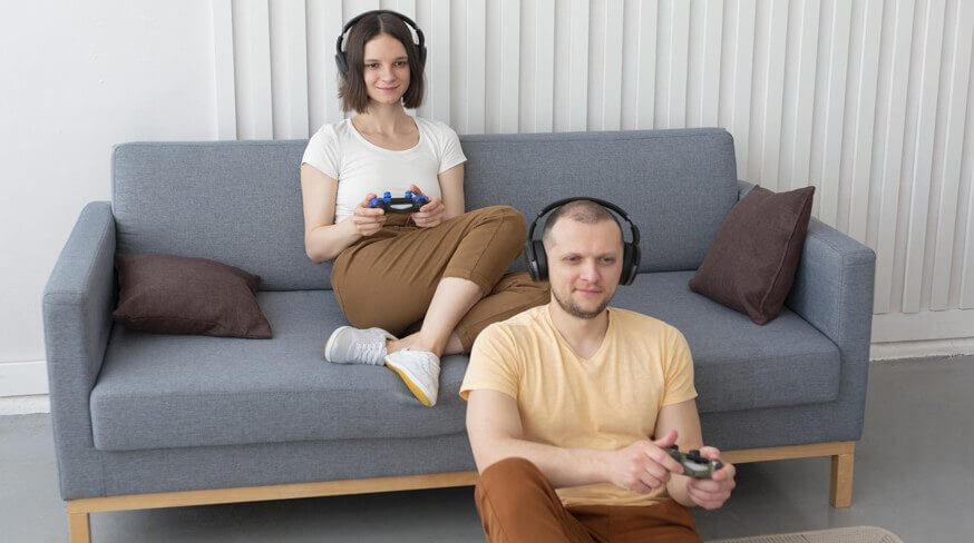 casal geek jogando videogame no sofá