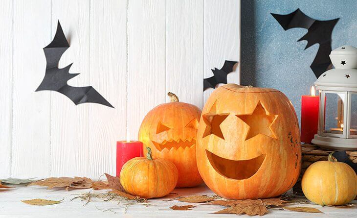 decoração de halloween com abóboras com rostos e morcegos de papel